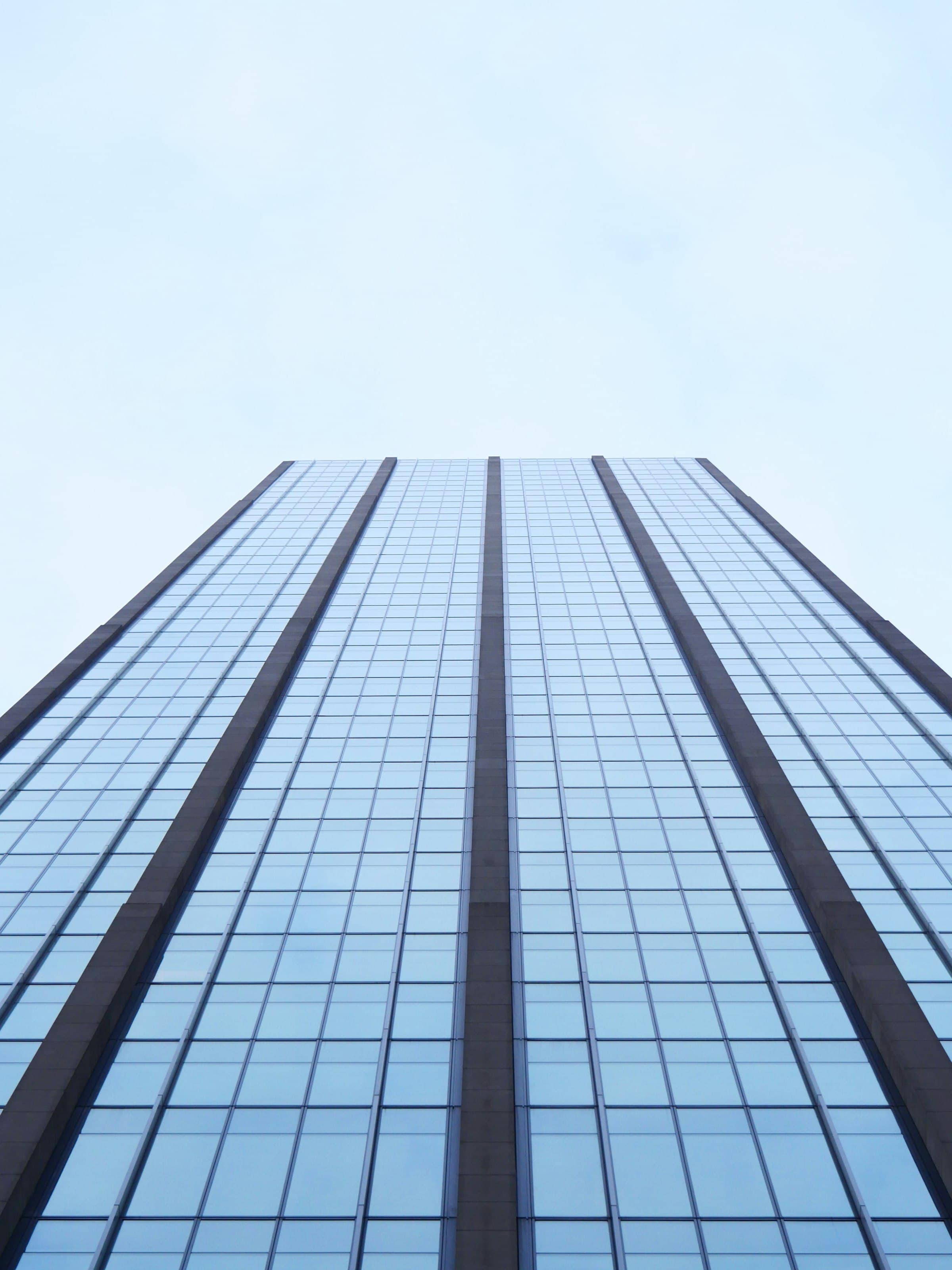 Glass office tower photographed from street level, converging toward the sky