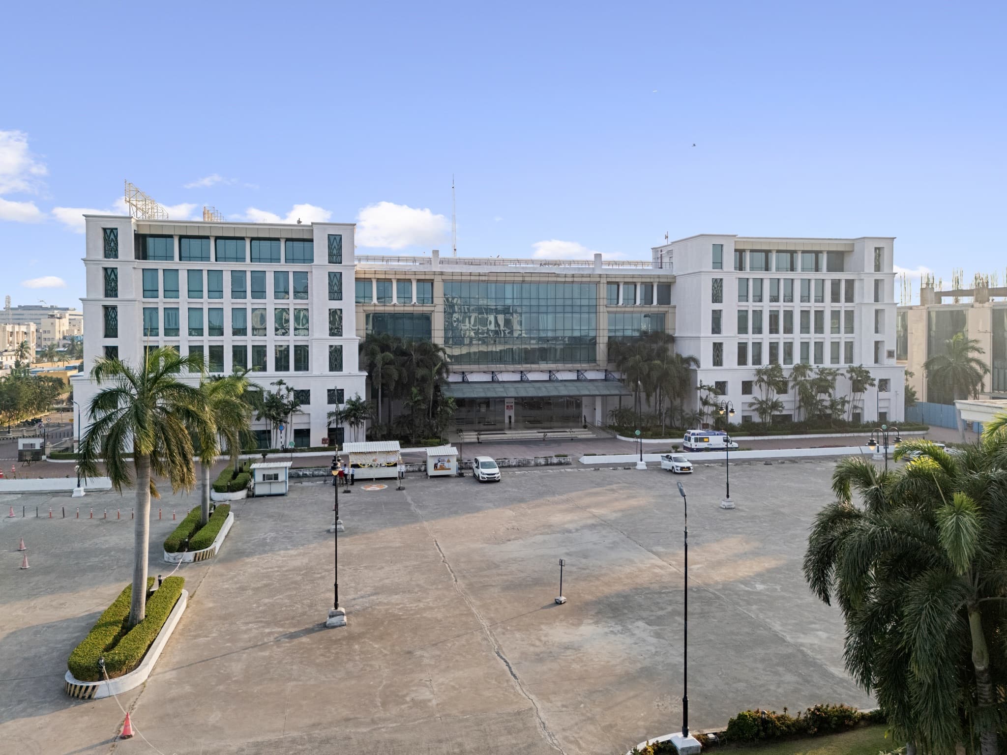 The main block of Sandhya Infocity, a central glass atrium between two stone-clad wings fronting the campus plaza