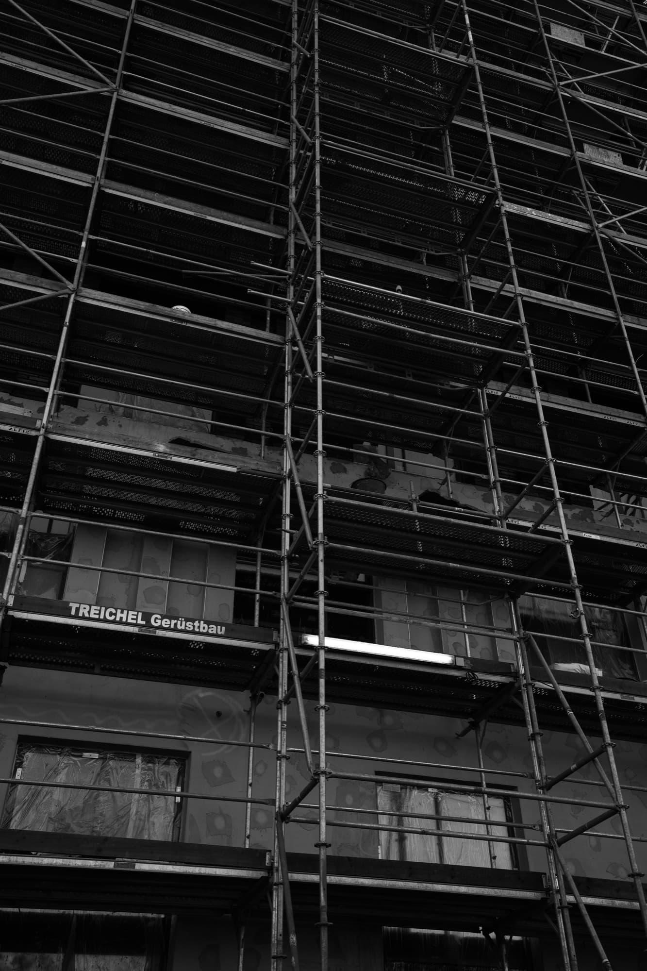 Scaffolding members forming a repeating geometric grid, in black and white