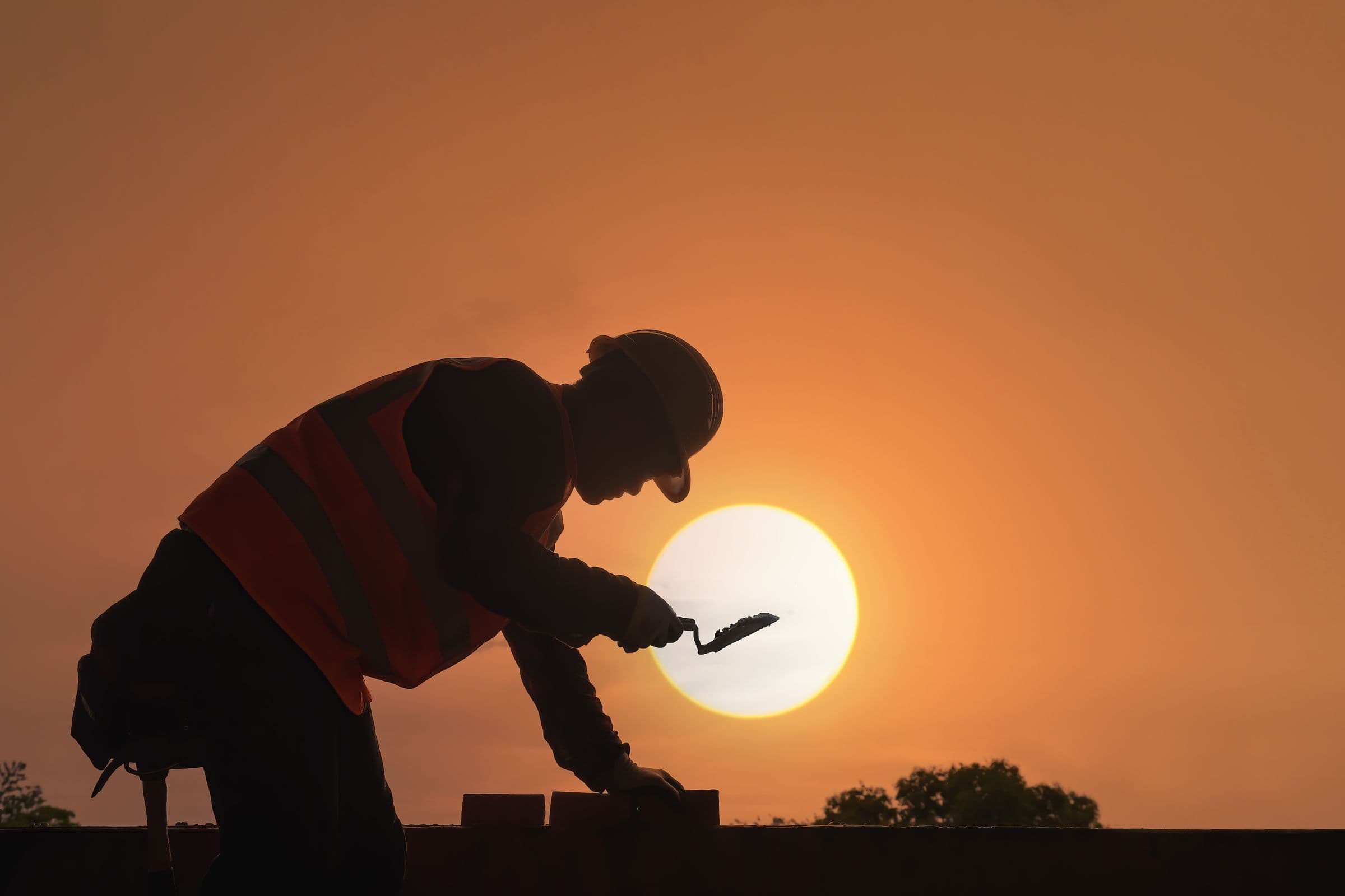 Construction worker silhouetted against the setting sun